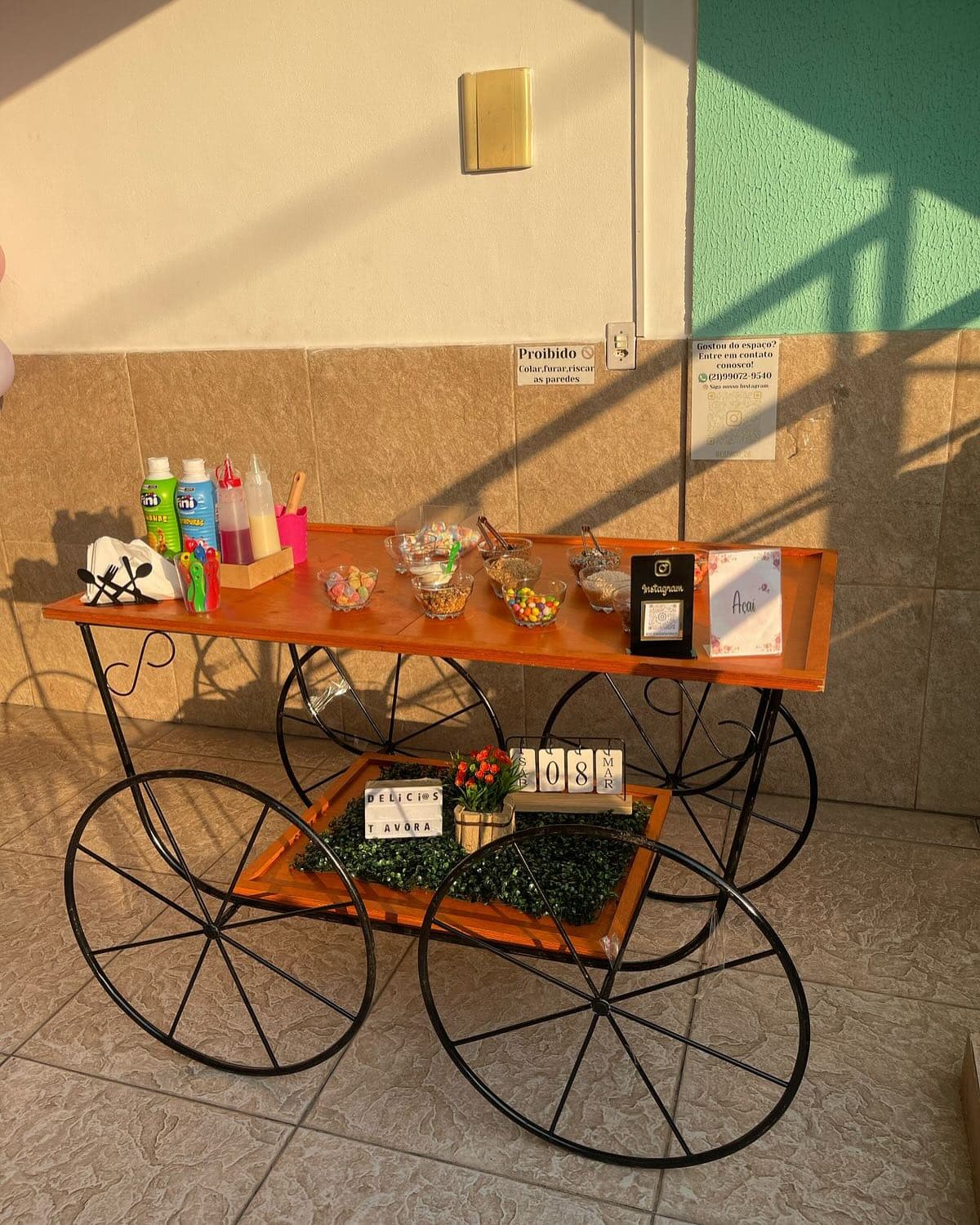Carrinho de estação montado com mesa, rodas e acompanhamentos visíveis.