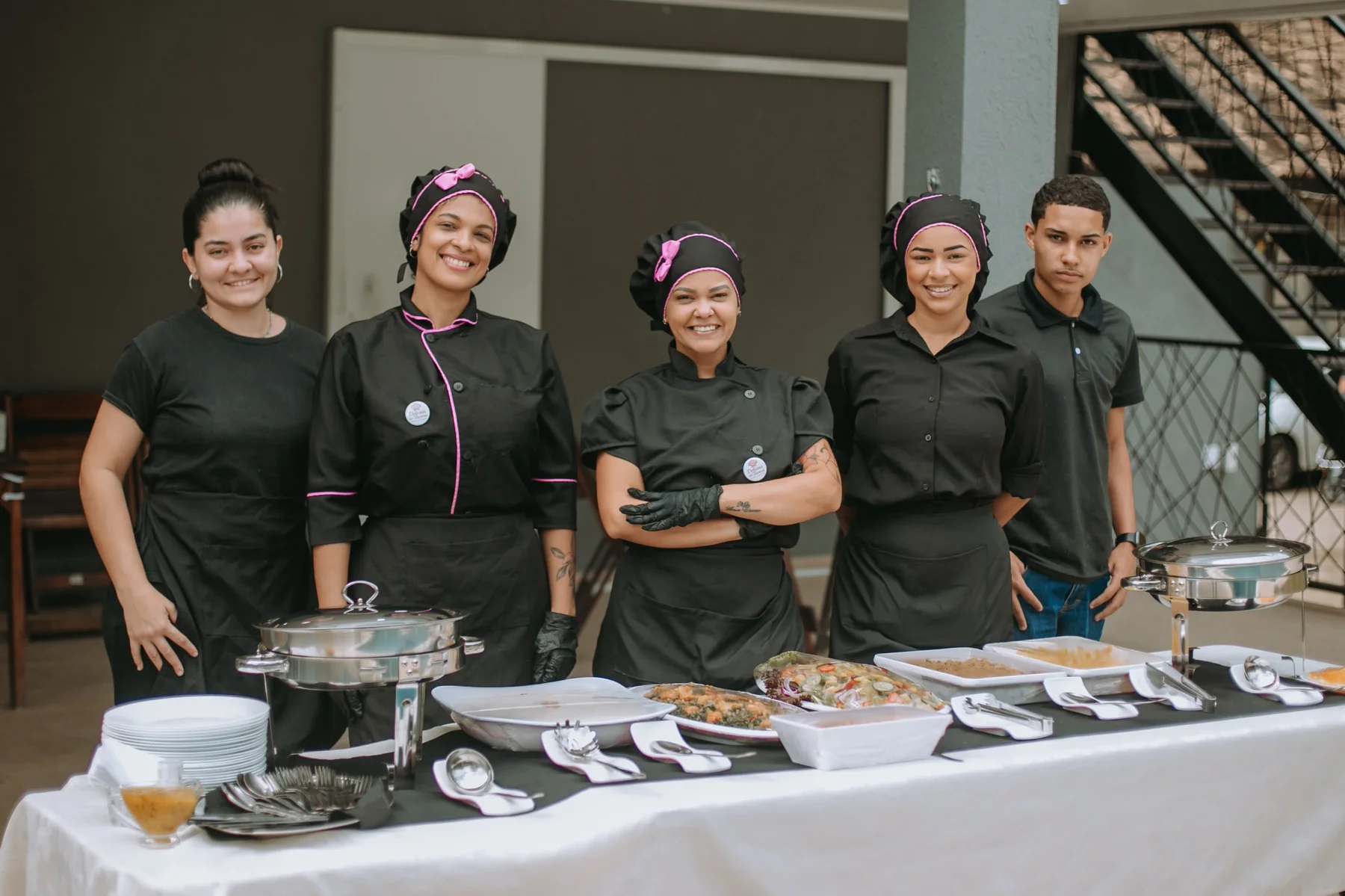 Equipe profissional em evento com mesa de buffet montada.